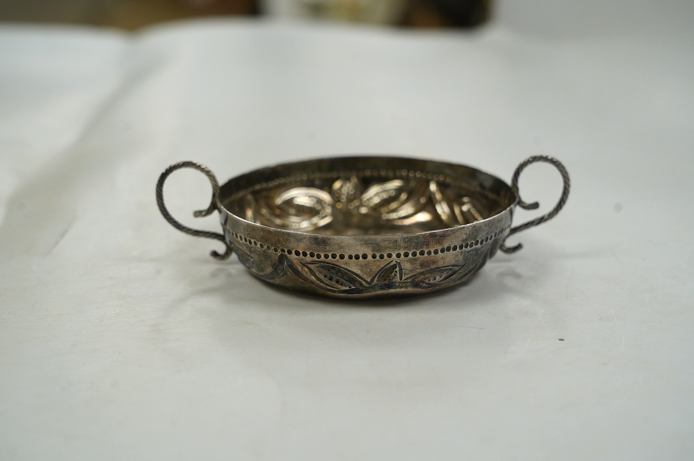 An Edwardian 17th century style Britannia standard silver porringer, by Maurice Freeman, London, circa 1905, 12cm, over handles. Condition - fair